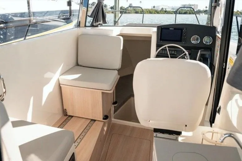 Slide: The Image of 2026 Bayliner Trophy T25 Pilothouse interior with seating and helm, overlooking water. - 8