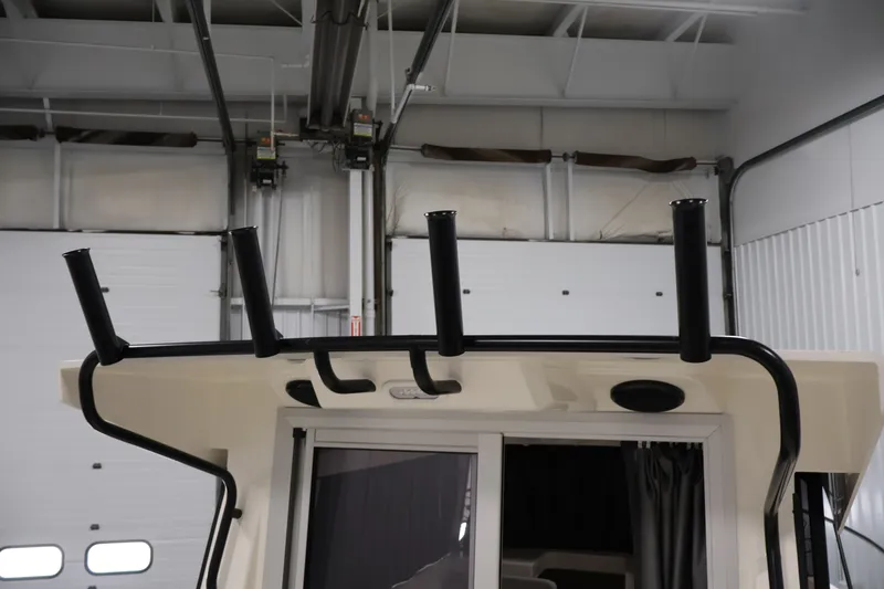 Slide: The Image of 2026 Bayliner Trophy T25 Pilothouse roof with rod holders in a garage setting. - 71