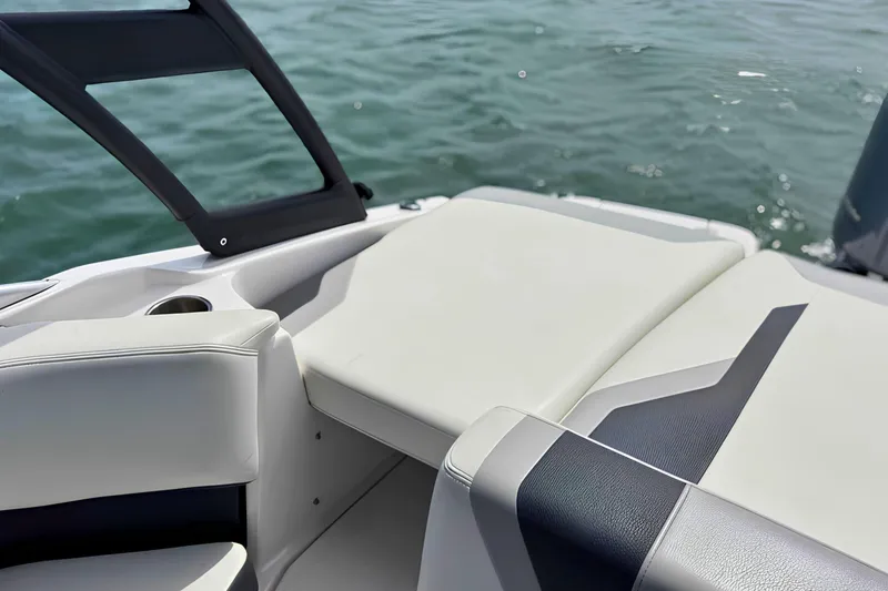 Slide: The Image of 2019 Regal 21 OBX boat interior with cushioned seating and cup holder, on calm water. - 11