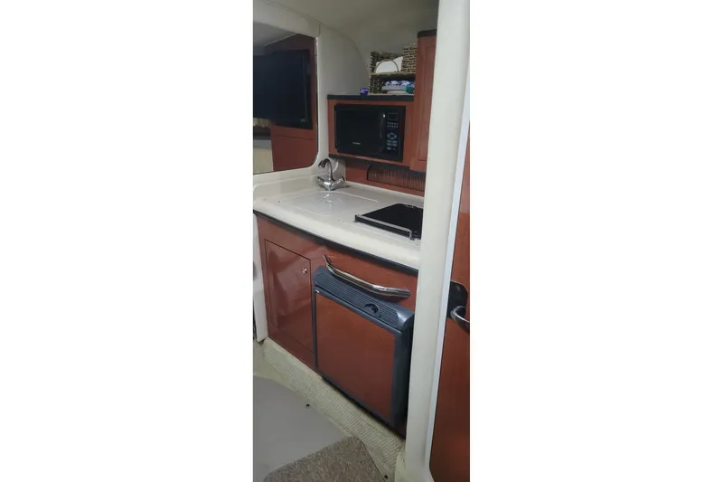 Slide: The Image of 2004 Sea Ray Sundancer 280 interior kitchen with sink, microwave, and cabinetry. - 27