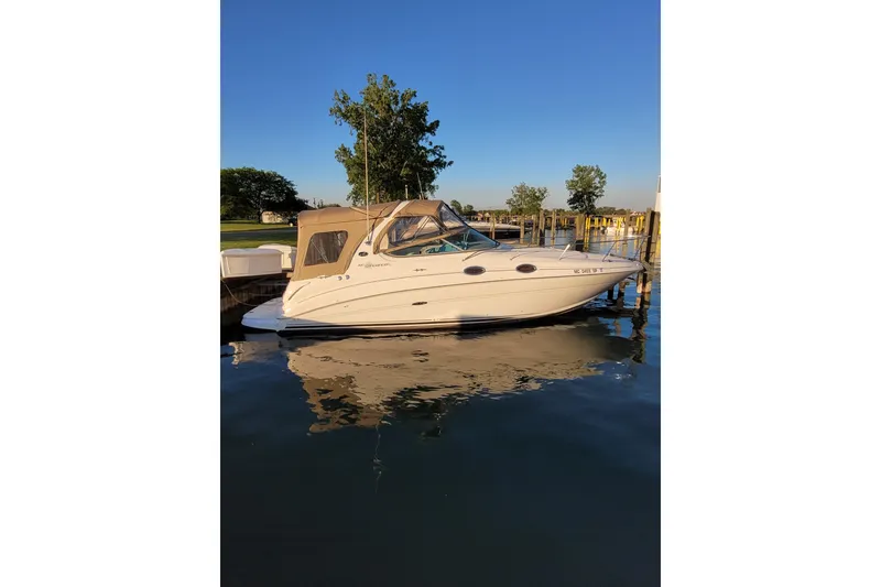 Slide: The Image of 2004 Searay 280 Sundancer boat docked on calm water under clear blue sky. - 5