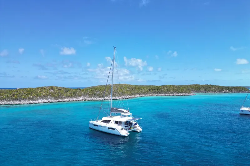 Slide: The Image of 2020 Leopard 40 catamaran sailing in clear turquoise waters near a lush island. - 6