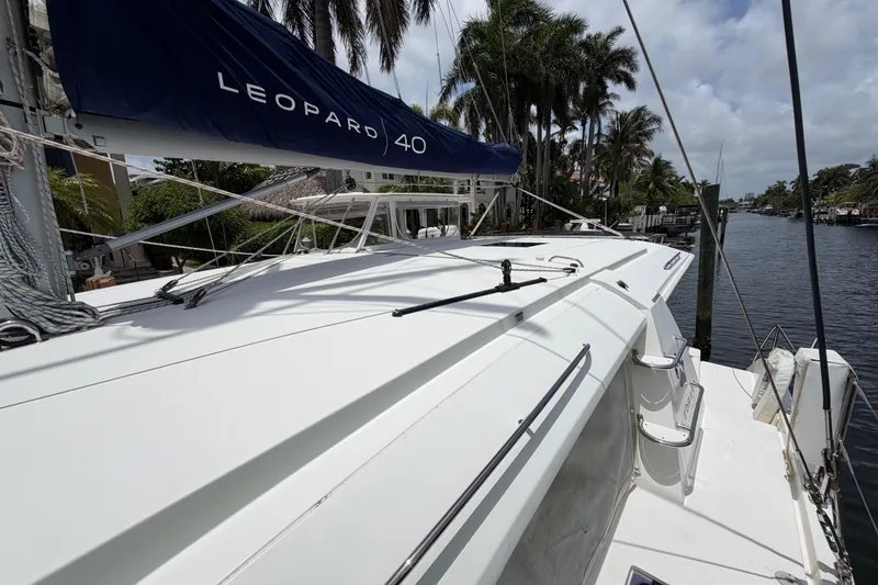Slide: The Image of 2020 Leopard 40 catamaran docked by palm trees, showcasing sleek design and spacious deck. - 82