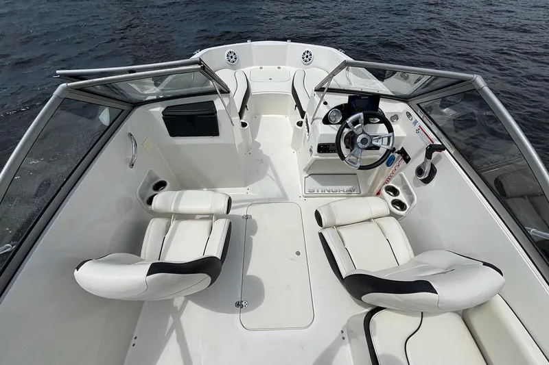 Slide: The Image of 2020 Stingray 191 DC boat interior with white seating and steering wheel on water. - 15