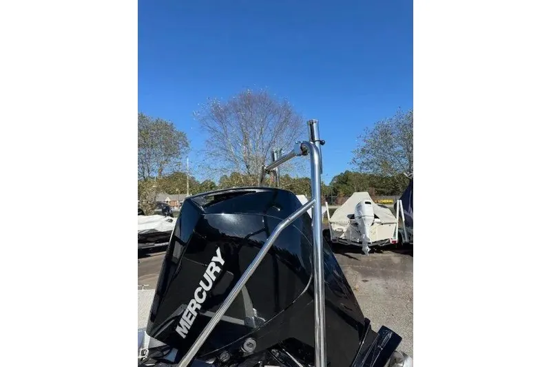 Slide: The Image of 2023 Bennington 23 SX with Mercury outboard motor, parked outdoors under clear blue sky. - 11