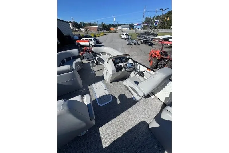 Slide: The Image of 2023 Bennington 23 SX pontoon boat interior with helm and seating, displayed outdoors. - 7