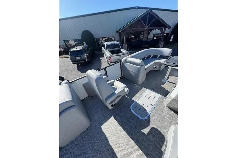 Slide: The Image of 2023 Bennington 23 SX pontoon boat interior with seating and table, parked outdoors. - 8