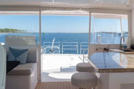 Slide: The Image of Luxurious Horizon PC65 yacht interior with ocean view, featuring modern seating and kitchen area, 2022 model. - 21