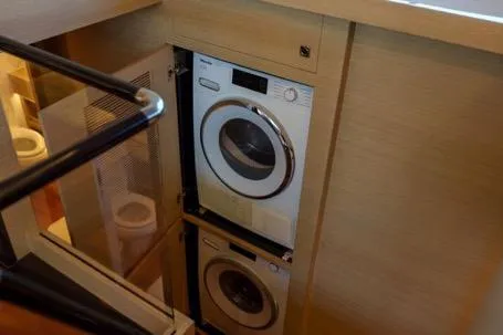 Slide: The Image of 2022 Horizon PC65 yacht interior with stacked washer and dryer units. - 99