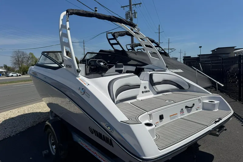 Slide: The Image of 2026 Yamaha Boats 195S, sleek white design, parked outdoors on a sunny day. - 2
