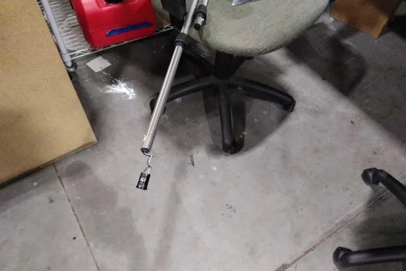 Slide: The Image of Office chair on concrete floor with a metal rod and hook nearby. - 49