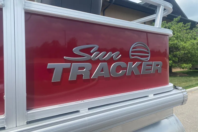Slide: The Image of Sun Tracker Bass Buggy 18 DLX 2026 model, red exterior with logo, parked outdoors. - 2