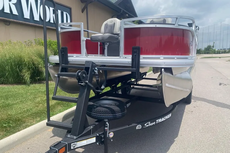 Slide: The Image of 2026 Sun Tracker Bass Buggy 18 DLX pontoon boat on trailer, parked outdoors. - 3