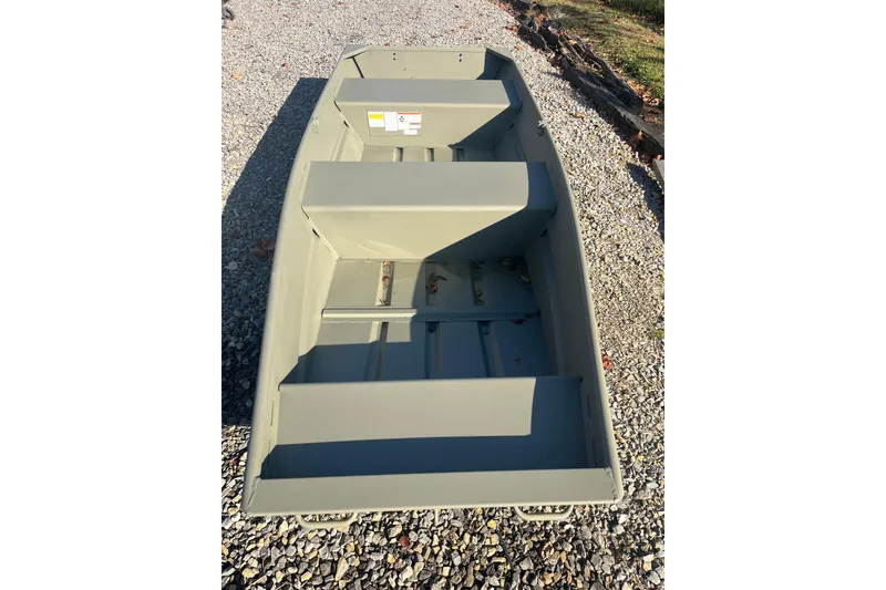Slide: The Image of 2026 Tracker Grizzly 12 Jon boat on gravel, showcasing interior seating and structure. - 2