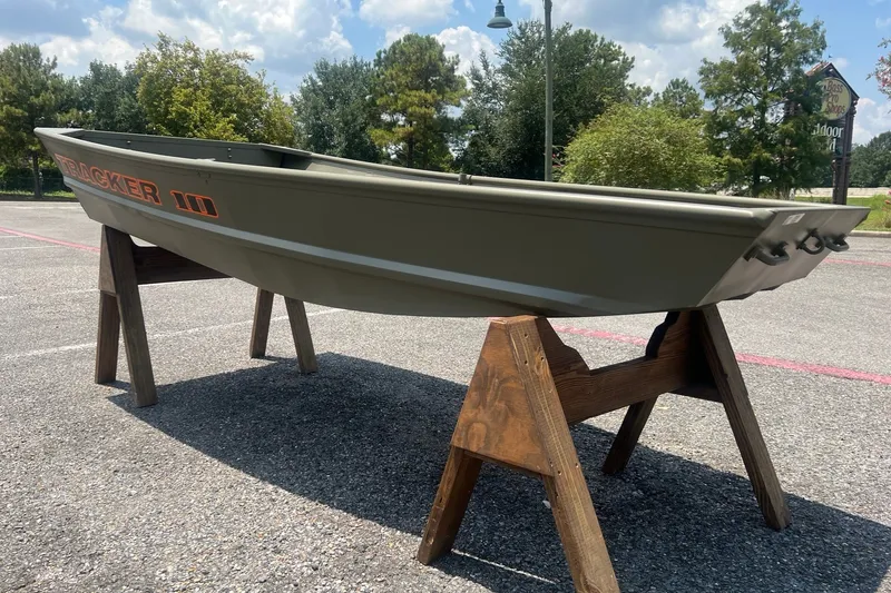 Slide: The Image of 2026 Tracker Grizzly 10 Jon boat displayed on wooden stands outdoors. - 3
