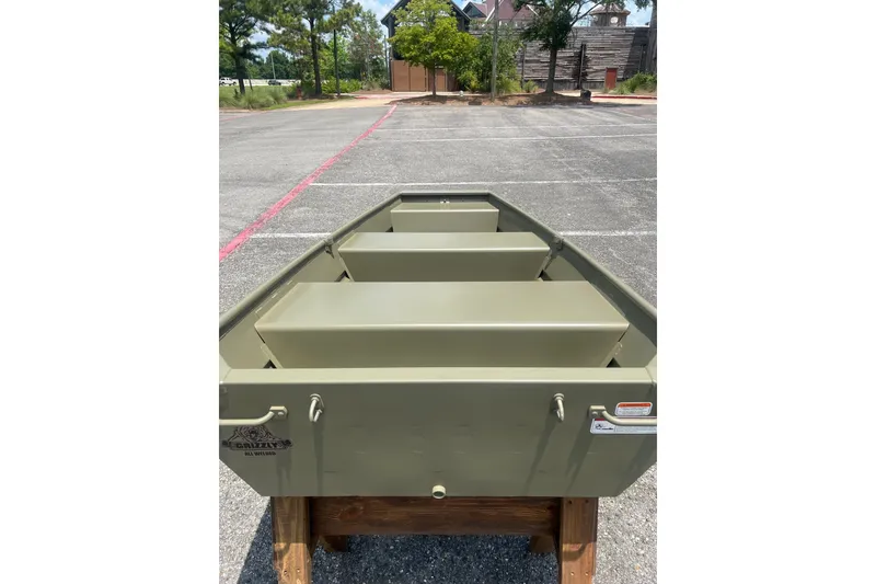 Slide: The Image of 2026 Tracker Grizzly 10 Jon boat displayed outdoors on a wooden stand. - 10