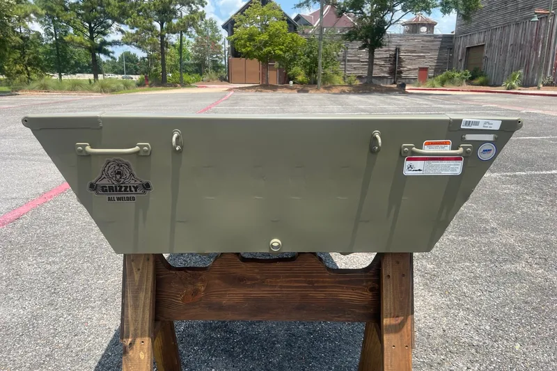 Slide: The Image of 2026 Tracker Grizzly 10 Jon boat displayed outdoors on a wooden stand. - 2