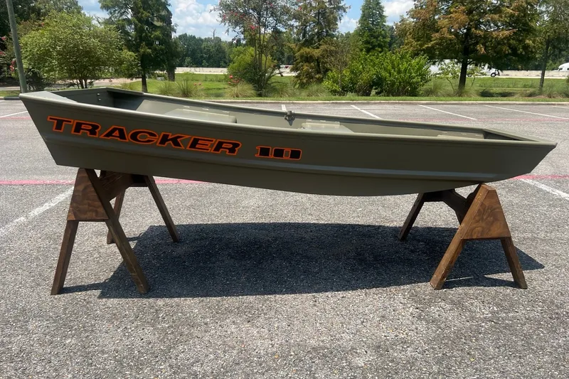 The Image of 2026 Tracker Grizzly 10 Jon boat displayed on wooden stands in a parking lot. - 0