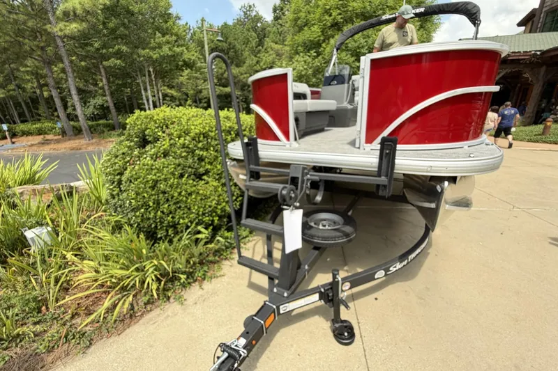 Slide: The Image of 2026 Sun Tracker Party Barge 16 DLX pontoon boat on trailer, surrounded by greenery. - 4