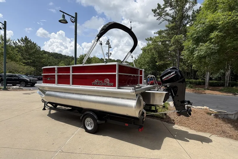 Slide: The Image of 2026 Sun Tracker Party Barge 16 DLX pontoon boat with Mercury outboard motor, parked outdoors. - 2
