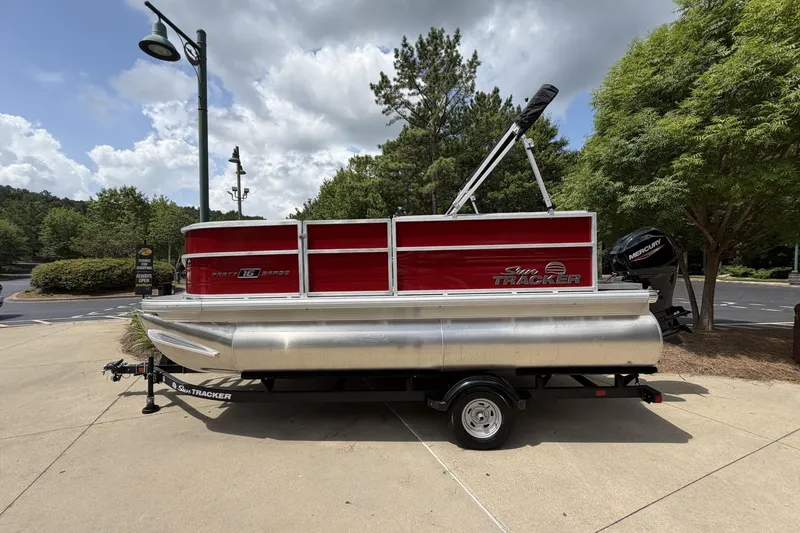 The Image of 2026 Sun Tracker Party Barge 16 DLX pontoon boat on trailer, parked outdoors. - 0