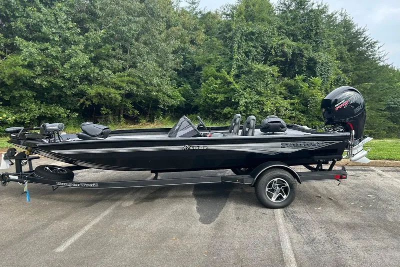 The Image of 2026 Ranger RT198P boat on trailer, parked near lush green trees. - 0