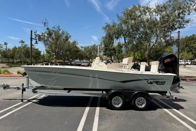 Slide: The Image of 2026 Mako Pro Skiff 19 CC boat on trailer in parking lot, sunny day. - 1