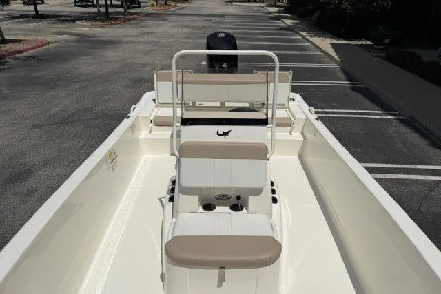 Slide: The Image of 2026 Mako Pro Skiff 19 CC boat interior with seating and console in a parking lot. - 7