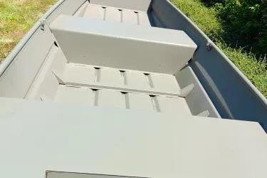 Slide: The Image of 2026 Tracker Grizzly 14 Jon boat interior with bench seats and green surroundings. - 5