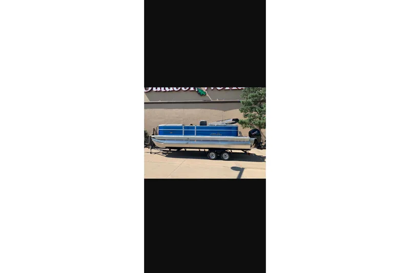 Slide: The Image of 2026 Sun Tracker Party Barge 22 XP3 pontoon boat on trailer, parked outdoors. - 28
