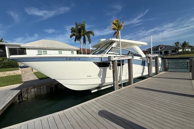 The Image of 2021 World Cat 400 DC-X boat docked, surrounded by palm trees and waterfront homes. - 1