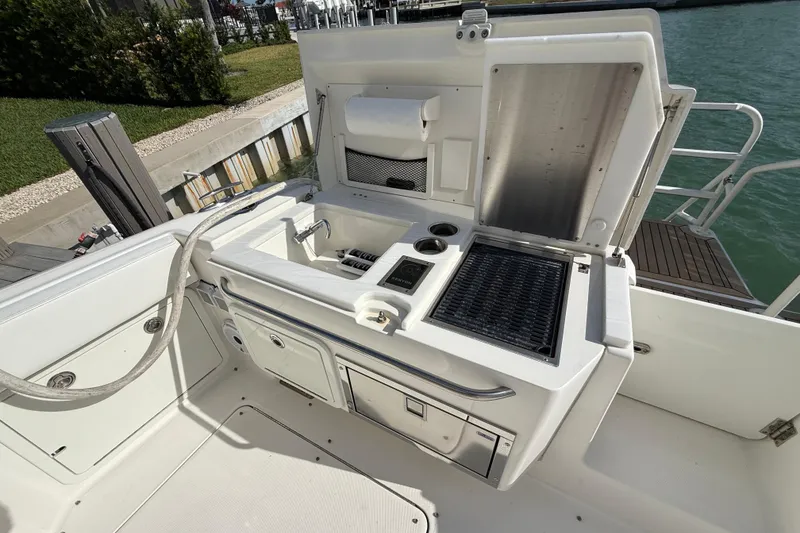 Slide: The Image of Outdoor kitchen area on a 2021 World Cat 400 DC-X boat, featuring a grill and sink. - 23