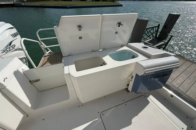 Slide: The Image of 2021 World Cat 400 DC-X boat with Yamaha engine, featuring open storage compartments by the water. - 24