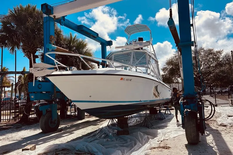 The Image of 2006 Contender 35 Side Console boat on lift, surrounded by palm trees and blue sky. - 0