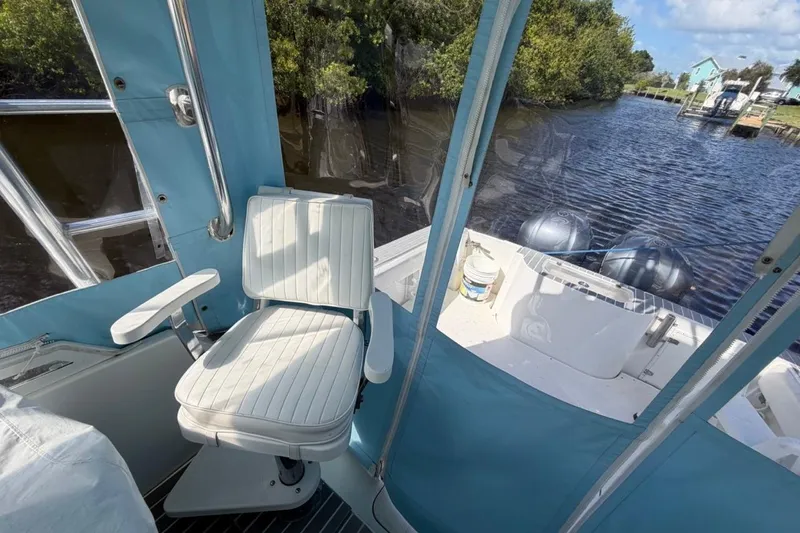 Slide: The Image of 2006 Contender 35 Side Console boat interior with white seating and blue canopy on a sunny day. - 8