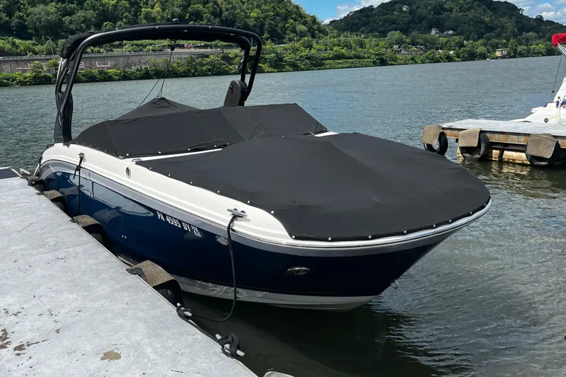 Slide: The Image of 2019 Sea Ray SDX 270 boat docked with black cover on a sunny day. - 2
