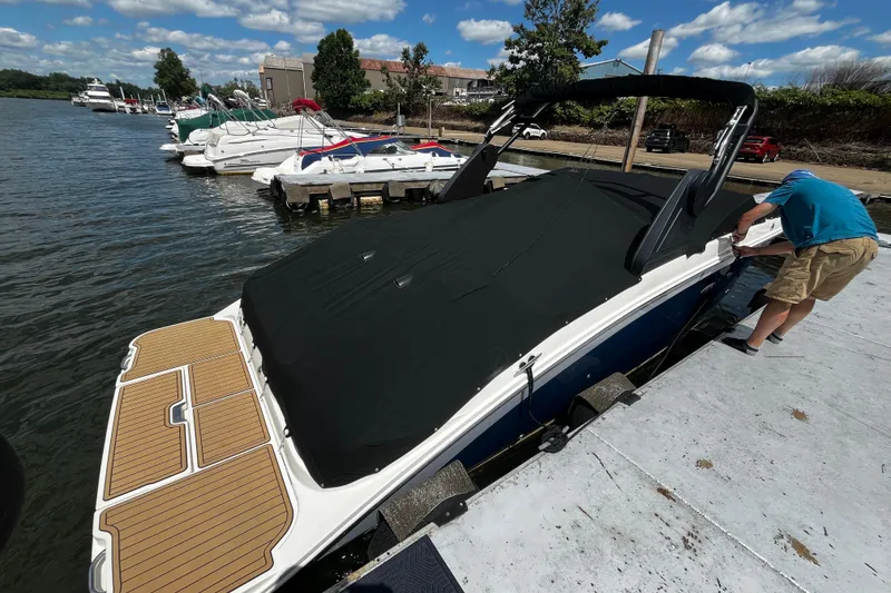 Slide: The Image of 2019 Sea Ray SDX 270 boat docked, covered, with a person securing it. - 4