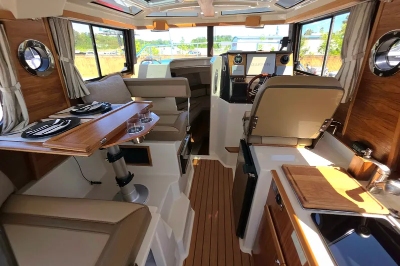 Slide: The Image of Interior of 2025 Ranger Tugs R-25, featuring modern seating, dining area, and navigation controls. - 16