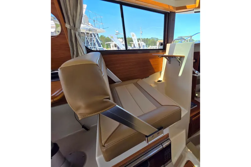 Slide: The Image of Interior of 2025 Ranger Tugs R-25, featuring a comfortable helm seat and window view. - 17