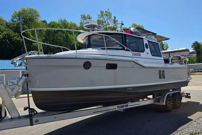 Slide: The Image of 2025 Ranger Tugs R-25 boat on trailer, parked outdoors under clear sky. - 2
