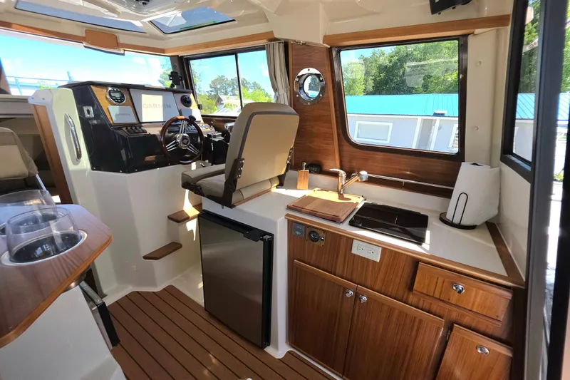 Slide: The Image of Interior of 2025 Ranger Tugs R-25, featuring helm, kitchenette, and modern wood finishes. - 20