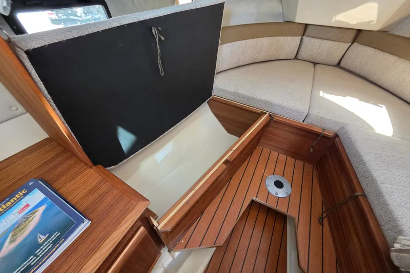 Slide: The Image of 2025 Ranger Tugs R-25 interior with wooden flooring and cushioned seating area. - 22