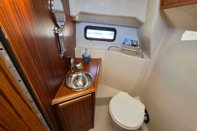 Slide: The Image of 2025 Ranger Tugs R-25 boat bathroom with wooden cabinetry and stainless steel sink. - 24