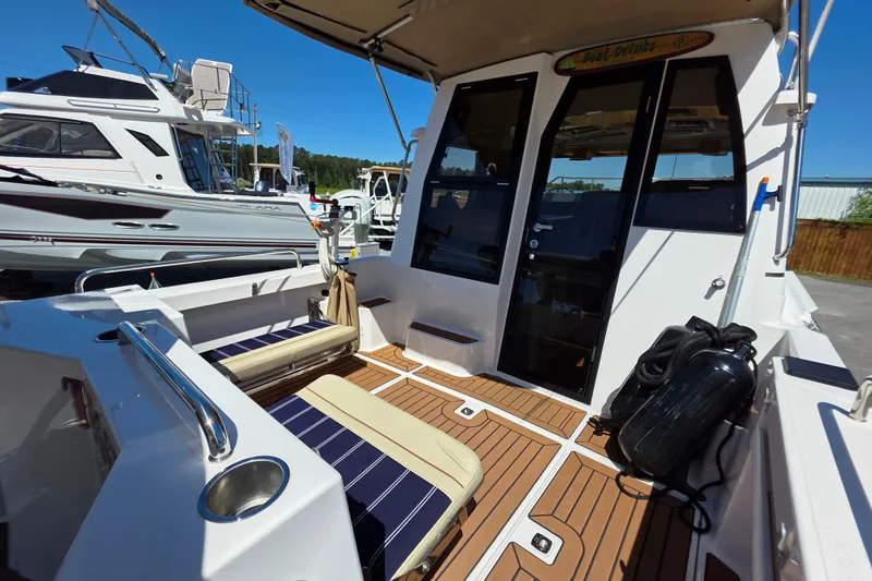 Slide: The Image of 2025 Ranger Tugs R-25 boat deck with seating and teak flooring at a marina. - 7