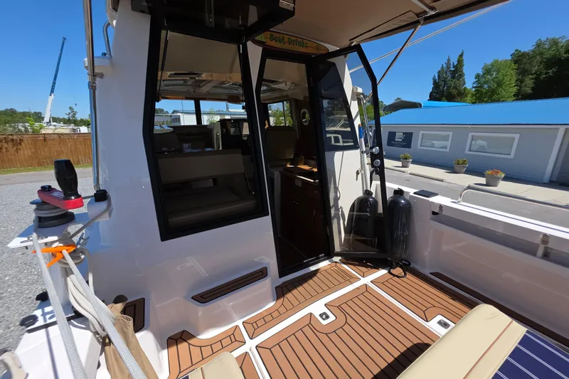 Slide: The Image of 2025 Ranger Tugs R-25 boat interior with open door, showcasing seating and deck details. - 9