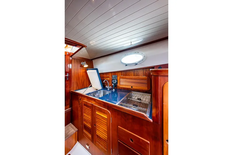 Slide: The Image of 2001 Hinckley Picnic Boat 36 Classic interior with wooden cabinetry and compact kitchen area. - 15