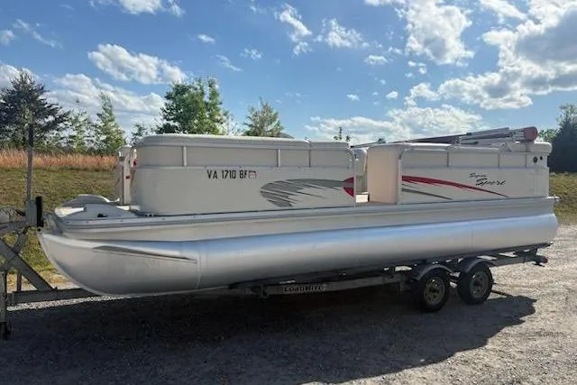 The Image of 2004 Bennington 2275LX pontoon boat on trailer under a clear blue sky. - 1
