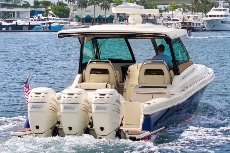 Slide: The Image of 2022 Chris-Craft Calypso 35 boat cruising with triple outboard engines in a marina setting. - 7