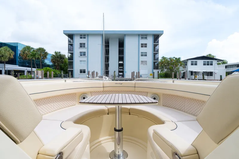 Slide: The Image of 2022 Chris-Craft Calypso 35 boat interior with seating and table, docked near modern buildings. - 26
