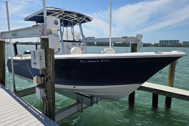 The Image of 2012 Sea Hunt Ultra 225 boat on lift, docked by waterfront with clear skies. - 1